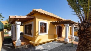 Un bâtiment jaune avec un toit en tuiles, des colonnes blanches et un petit porche.