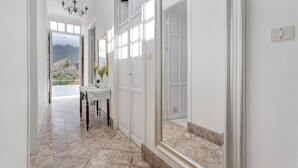 A hallway with a patterned floor, a table with a vase, and a chandelier.
