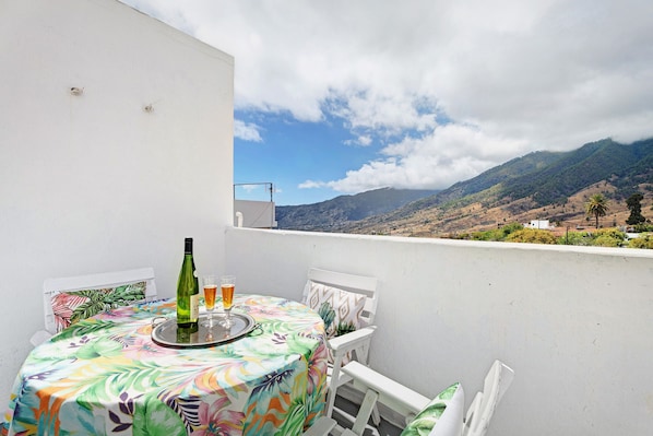 Un balcon avec une table dressée pour deux personnes, une bouteille et un verre de bière.