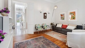 A living room with a sofa, chairs, a rug, a clock, and wall art.