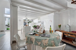 Una cocina moderna con armarios blancos, una mesa de comedor con mantel de mapa mundial y un aparador de madera con objetos decorativos.