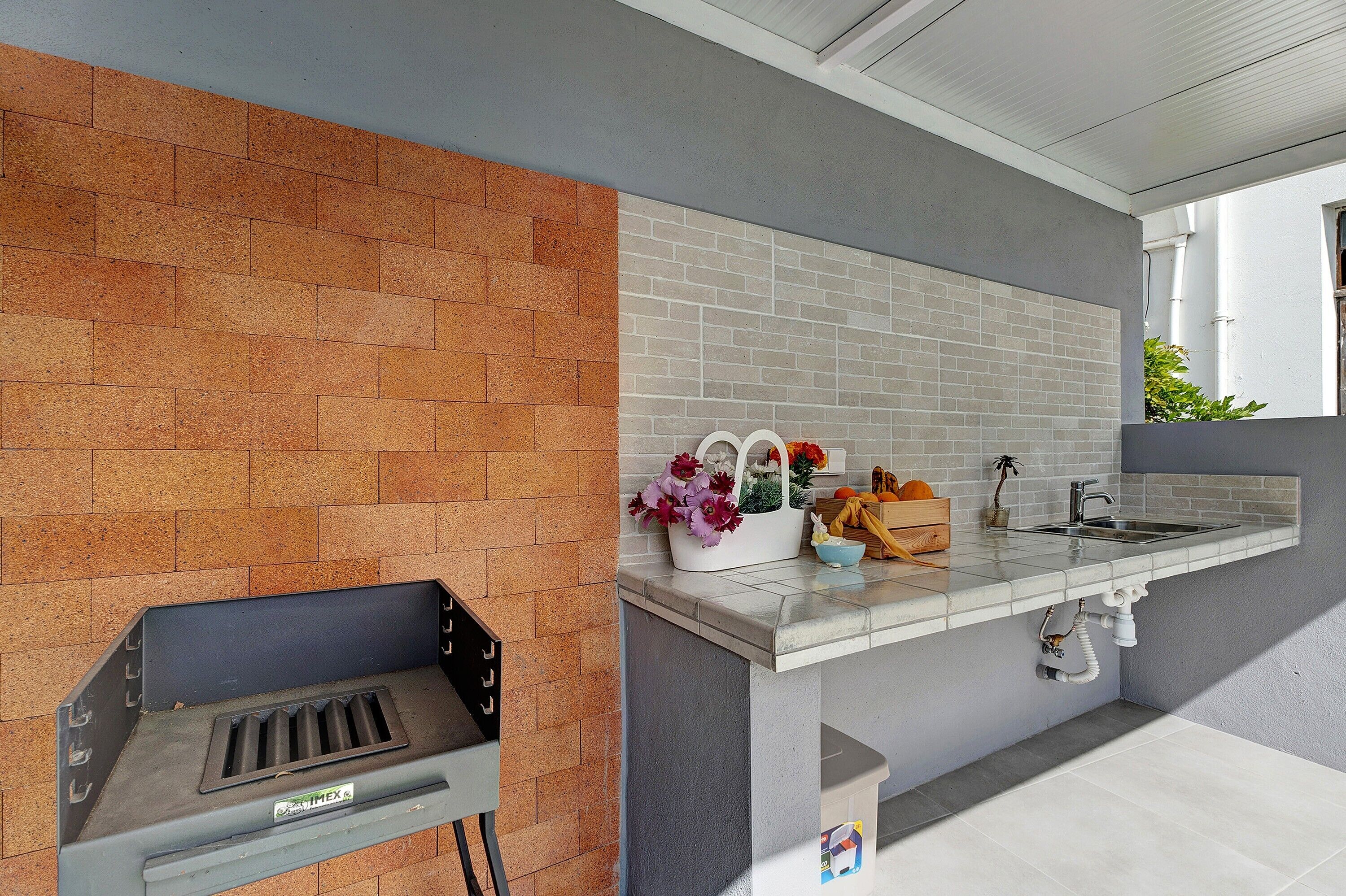 A kitchen with a brick backsplash, a built-in sink, and a small countertop.
