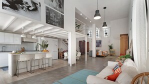 A spacious living area with a sofa, a dining table, and a kitchen area with bar stools.