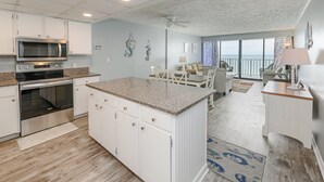 A kitchen with a microwave, oven, and granite countertop.