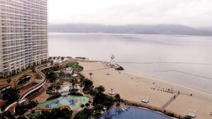 Un hôtel de grande hauteur doté d’une piscine, d’une plage et offrant une vue sur l’eau.