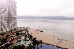 A high-rise hotel with a pool area, beach, and a view of the water. - Laimeng Shuixiewan Haiyi Holiday Apartment (Huidong)
