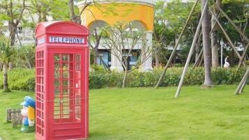 A red telephone booth in a grassy area with a building in the background.