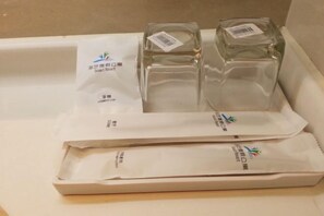 Un plateau contenant deux bouteilles en verre transparent et deux sacs en papier blanc ornés de texte et de logos.