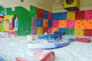 Une salle d’escalade dotée de murs colorés et recouverts de matelas, ainsi que de divers équipements d’escalade.