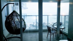 Un balcon avec un fauteuil suspendu, une table et des chaises.