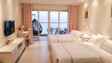 A hotel room with two beds, a TV, a desk, and a balcony with chairs.