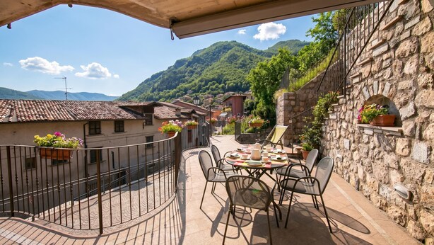 Une terrasse avec une table et des chaises, offrant une vue sur un paysage montagneux.