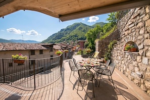 A terrace with a table and chairs, overlooking a mountainous landscape.