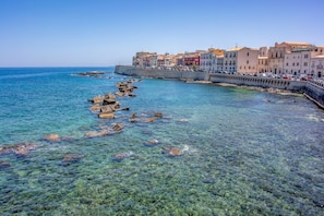 A coastal town with clear waters, rocky outcrops, and colorful buildings along the waterfront.
