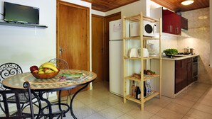Una cocina compacta con techo de madera, un área de comedor con una mesa redonda y sillas, y un estante empotrado para microondas.