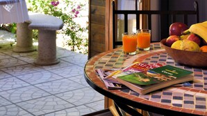 Comedor con mesa, sillas, un libro, un cuenco de fruta y un vaso de zumo de naranja.