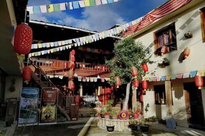 A courtyard with a wooden staircase, potted plants, and a tree. - Caiyunjian Inn (Shangri-La)