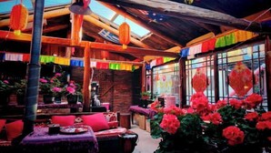 A cozy indoor space with wooden beams, colorful decorations, and potted plants. - Caiyunjian Inn (Shangri-La)