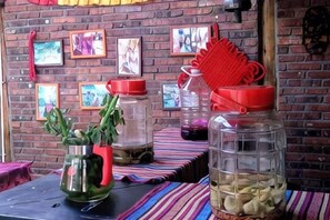 Une table sur laquelle se trouvent des bocaux contenant divers objets, un mur de briques orné de tableaux encadrés et un objet rouge accroché au mur.