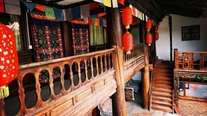 A traditional wooden staircase with a railing, leading to a room with patterned curtains and a wooden floor. - Caiyunjian Inn (Shangri-La)
