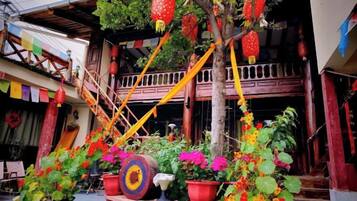 A traditional building with a balcony, potted plants, and hanging decorations.