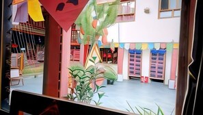 A colorful interior with a central plant, a staircase, and a patterned wall. - Caiyunjian Inn (Shangri-La)