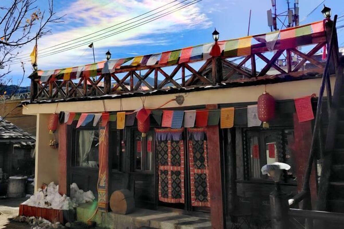 A traditional building with a wooden balcony, colorful prayer flags, and a red lantern.