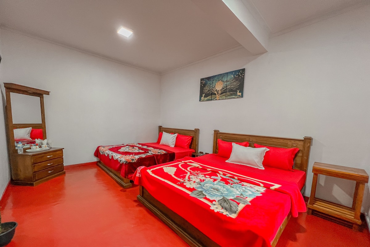 A bedroom with two beds, a nightstand, a dresser, and a painting on the wall.