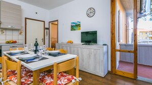 Un coin repas avec une table dressée pour quatre personnes, un téléviseur et une horloge au mur.