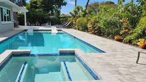 Une piscine rectangulaire dont le bord est revêtu de carreaux, entourée d’une terrasse dallée.