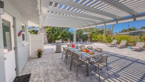 Une terrasse couverte avec une table à manger pour quatre personnes, entourée de chaises.