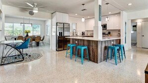 Une cuisine moderne dotée d’un îlot central, de tabourets de bar et d’un coin repas avec des chaises et une table.