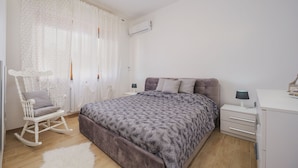 Une chambre à coucher avec un lit, un fauteuil à bascule, un bureau et une armoire.