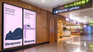 En lys og moderne lufthavnsterminal med en Sleepover butik og et skilt, der viser vejen til Sleep Lounge.
