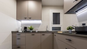 A modern kitchen with beige cabinetry, a stainless steel sink, and a black stove. - Acantilados by Interhome (Salou)