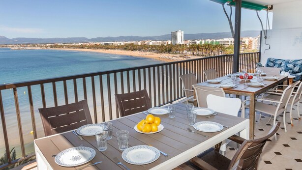 A balcony with a table set for two, overlooking a beach and ocean. - Acantilados by Interhome (Salou)