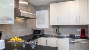 A modern kitchen with stainless steel appliances, white cabinets, and a black countertop. - Acantilados by Interhome (Salou)