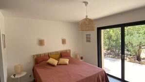 Una camera da letto moderna con un letto grande, un comodino, una lampada a sospensione e vista sull'esterno.