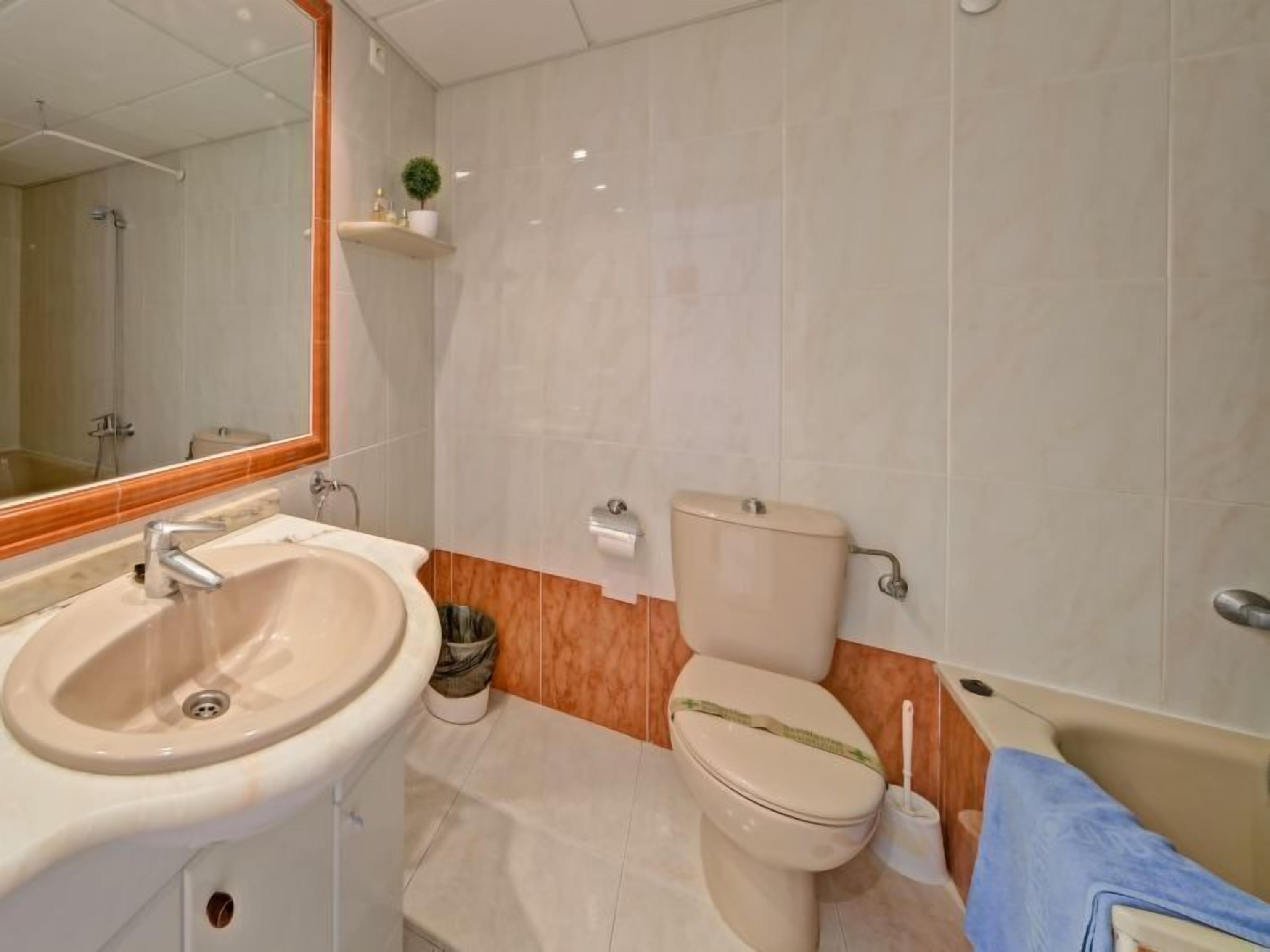 Une salle de bain avec un lavabo, des toilettes et un miroir.