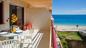 Ein Balkon mit Frühstückstisch, mit Blick auf einen Strand.