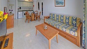 Ein Wohnzimmer mit einer Couch, einem Holztisch und einem Essbereich mit Stühlen und einem Tisch.