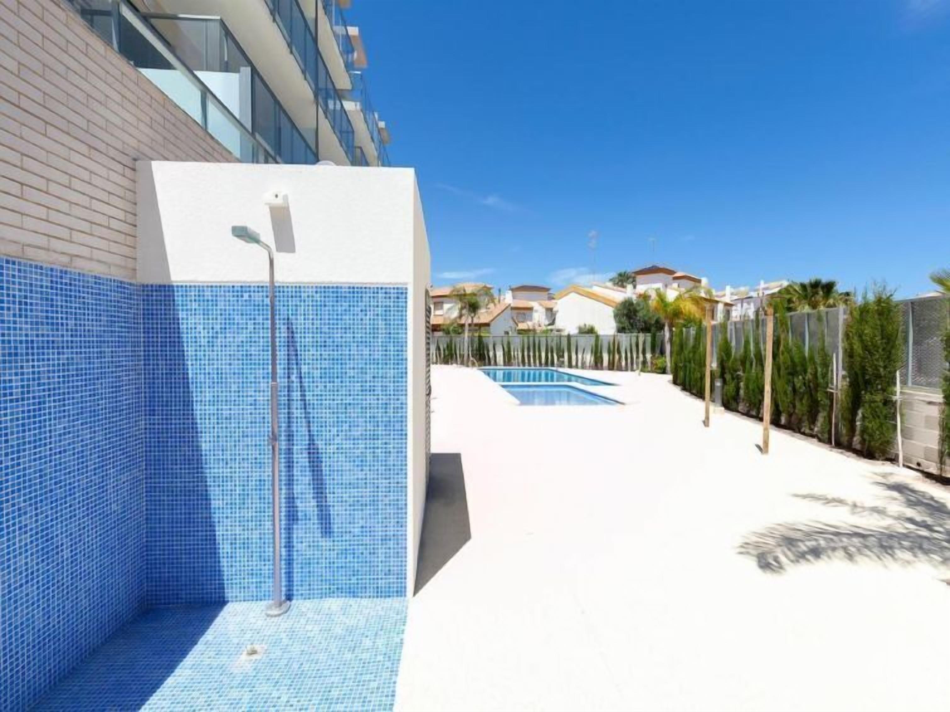 A swimming pool area with blue tiled walls and a clear sky.