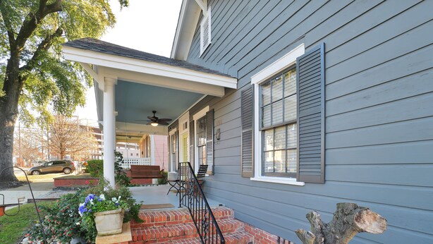 A house with a covered porch, a brick staircase, and a garden with a stone pathway. - Emma’s Cottage (Montgomery)