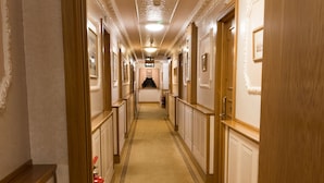 Ein Hotelkorridor mit Teppichboden, Holzvertäfelung und gerahmten Bildern an den Wänden.