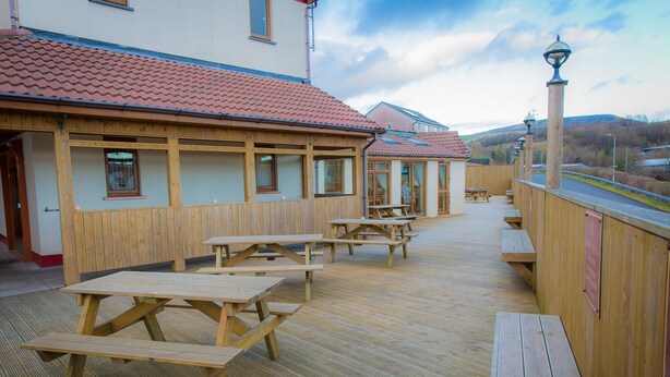 Eine Holzterrasse mit Picknicktischen und einem Holzzaun.