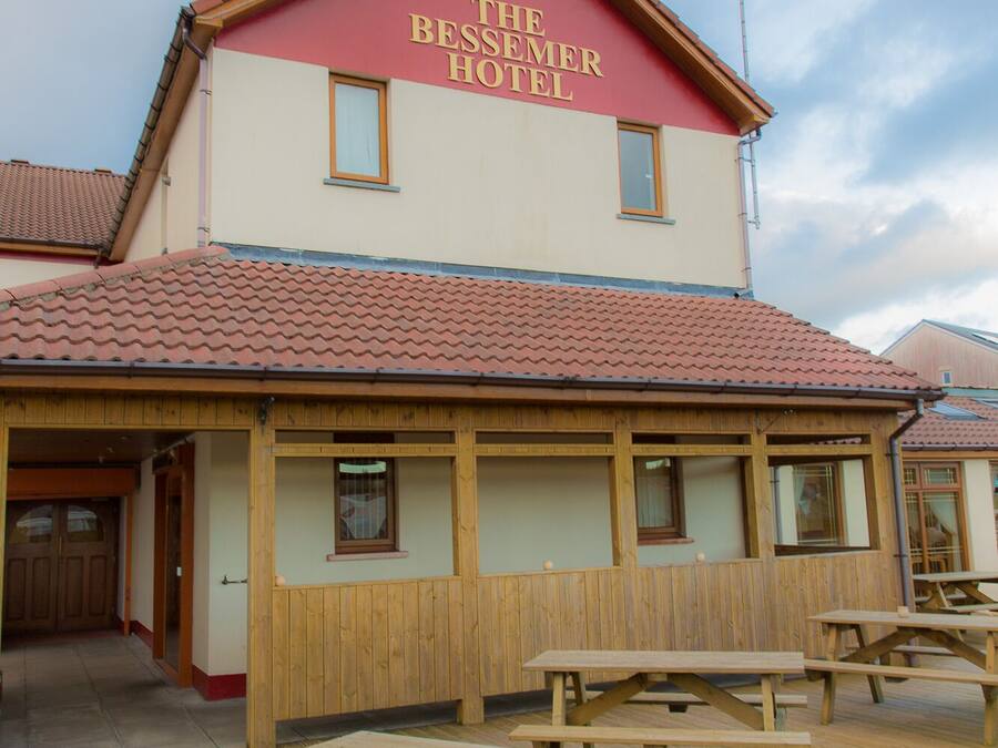 The Bessemer Hotel with a red roof, wooden exterior, and picnic tables on the deck.