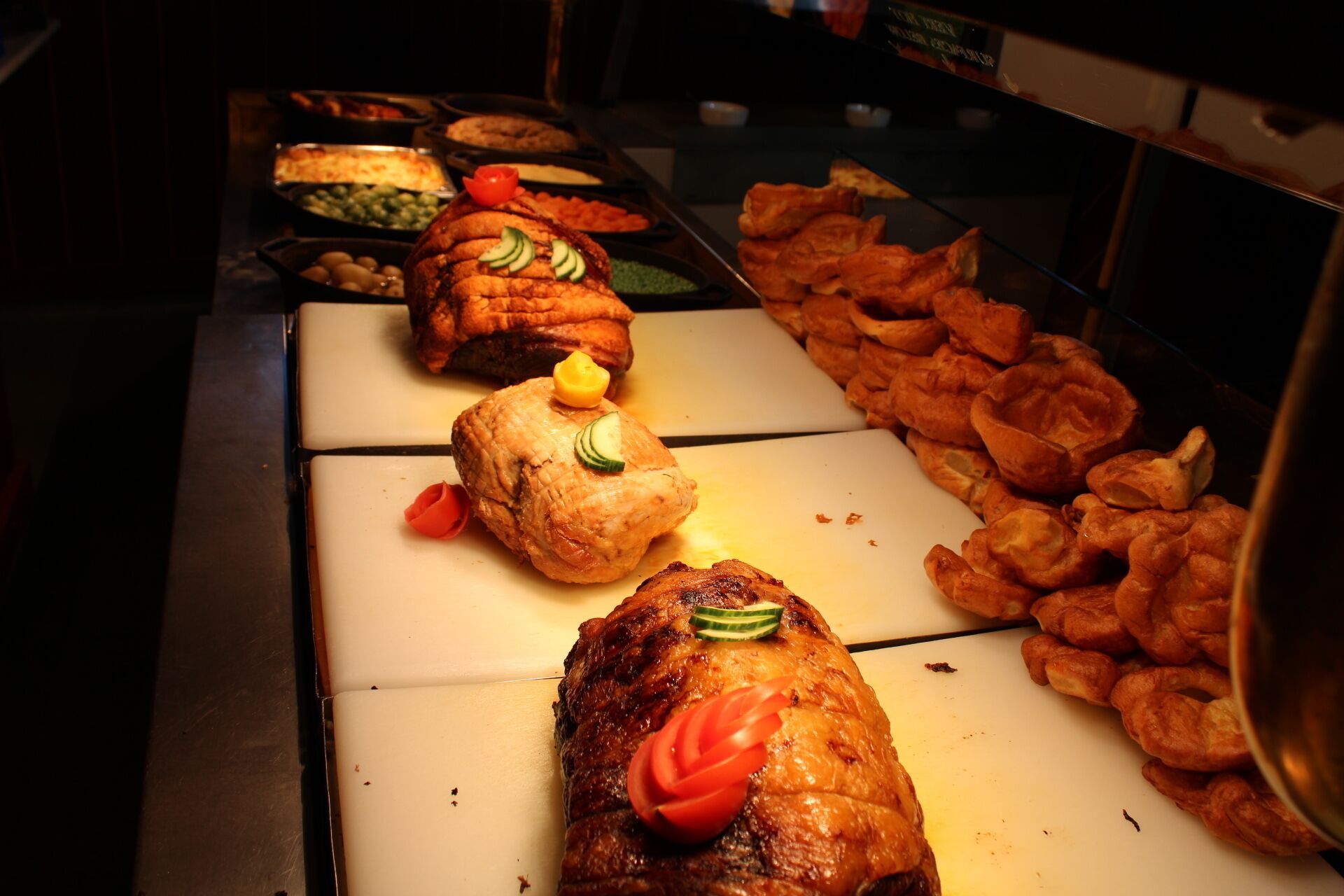 A buffet with various dishes including roasted meats, vegetables, and fried items.