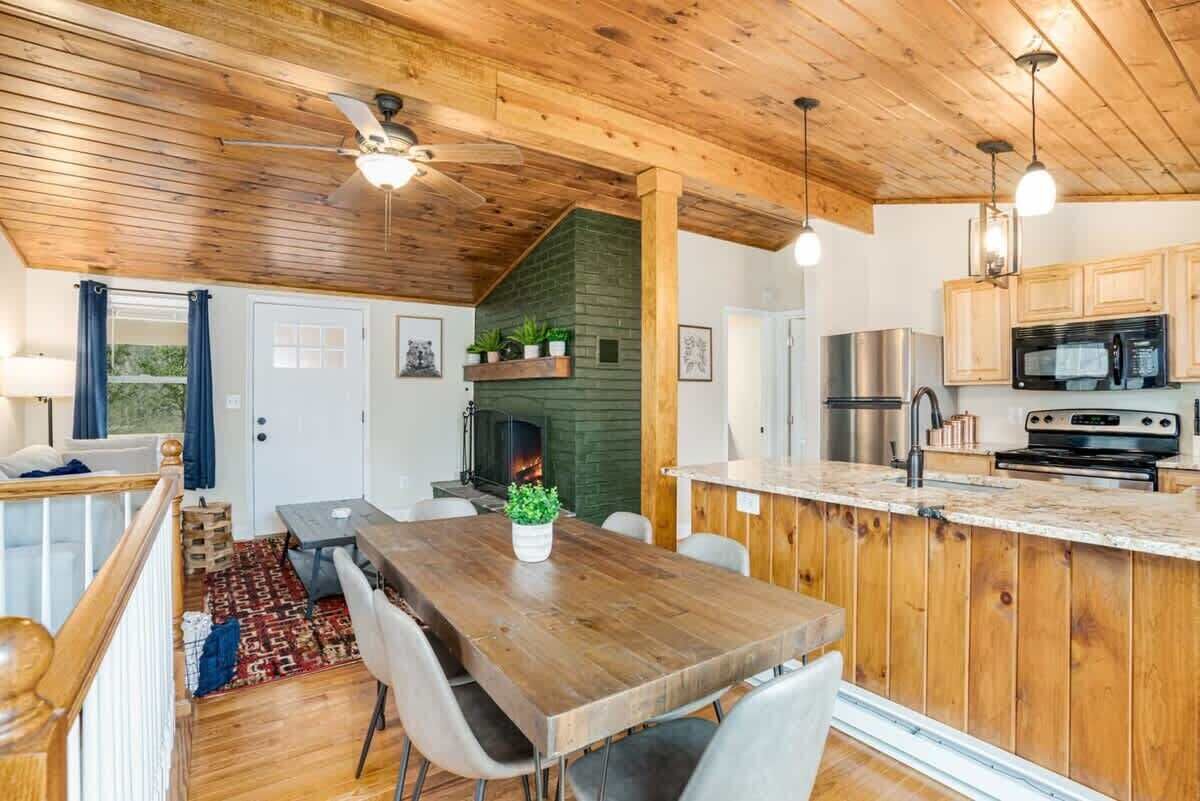 Eine gemütliche Küchenzeile im Blockhausstil mit Holzbalken, einer zentralen Kochinsel und einem Kamin.