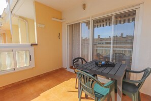 A balcony with a table and chairs, a sliding glass door, and a view of buildings.