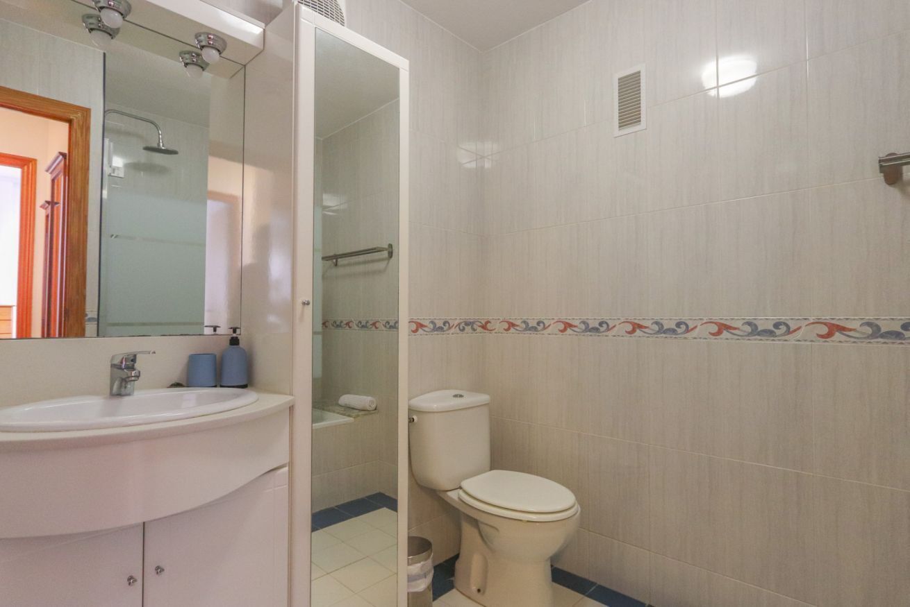 Une salle de bain avec un lavabo blanc, des toilettes et une douche.